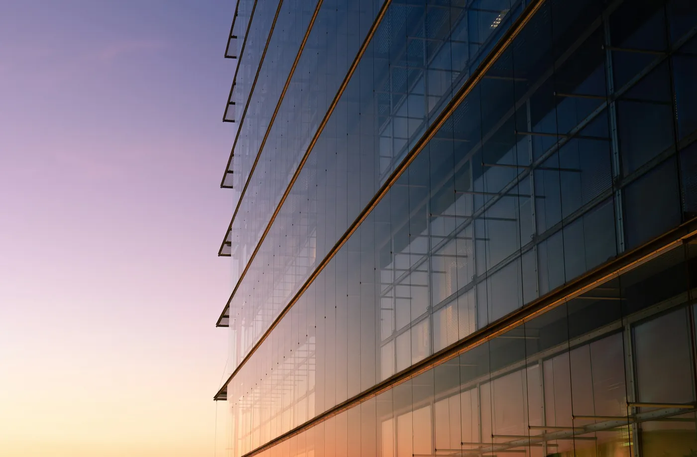 The glass facade of an office building at dusk
